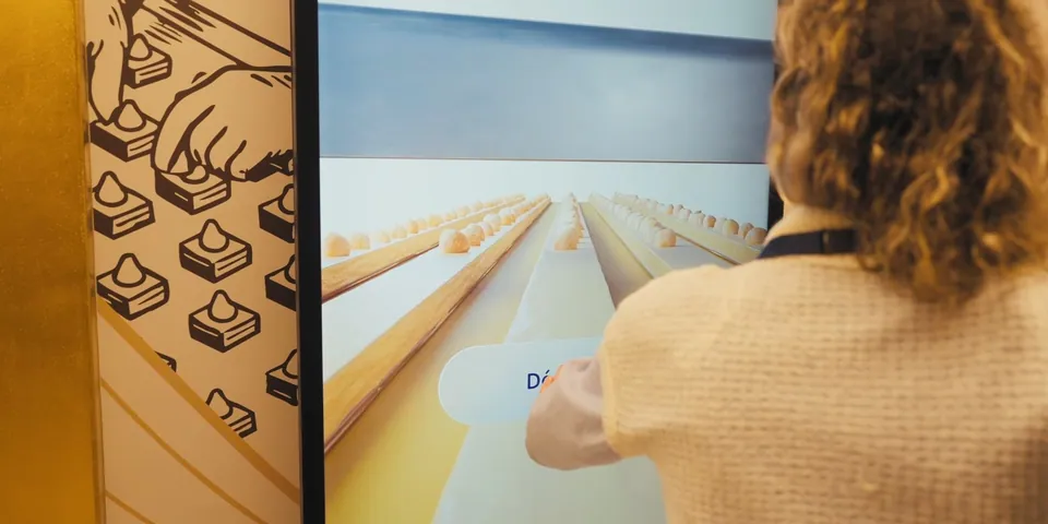 A visitor exploring how a praline is made on the touchscreen